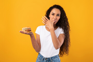 Happy Latin Lady Holding Burger Licking Finger At Studio