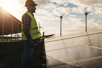 Man working for solar panels and wind farm turbines - Renewable energy concept - Focus on male...