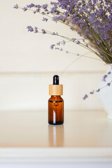 Amber glass bottles with dropper pipette with serum or essential oil on the on a nightstand with lavender flowers. Skin care products , natural cosmetic. Beauty concept for face and body care