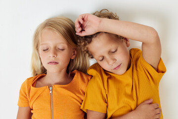 boy and girl lie on a white background in yellow t-shirts emotions