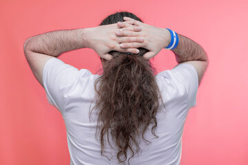 Close-up of a man with long hair holding his hands behind his head. Back view. Bracelet in the...