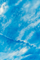 Blue sky with white clouds. Airplane dissipation trail tearing the sky and clouds.