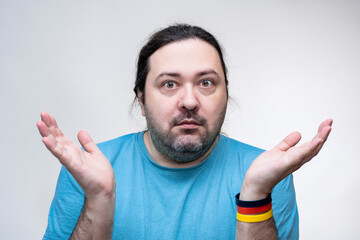 An adult, unshaven man spreads his hands in a gesture of surprise and does not understand what is happening. The bracelet is in the colors of the flag of Germany.