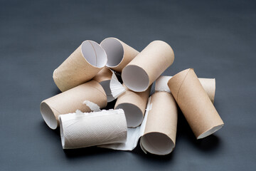 A bunch of empty toilet paper rolls. Cardboard tubes lying in a heap on a dark background. An image on the theme of the crisis and the lack of basic things and amenities.