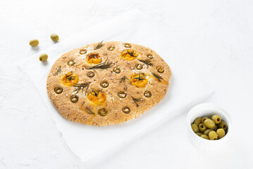 Vegan italian focaccia with olives, tomatoes, rosemary and spices on the table.