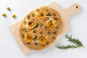 Vegan italian focaccia with olives, tomatoes, rosemary and spices on the table. Horizontal orientation, top view.