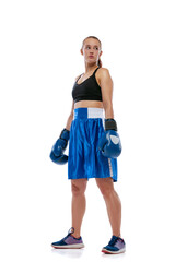 Portrait of young beautiful girl, professional boxer in boxing shorts and gloves posing isolated on white studio background. Concept of sport, studying, competition