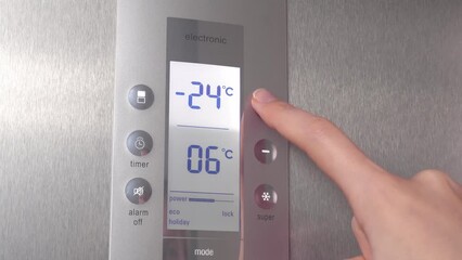 Refrigerator display with preset temperature for refrigerator and freezer. A woman's hand presses the buttons including freezing. refrigerator control panel in the apartment. Modern smart things.