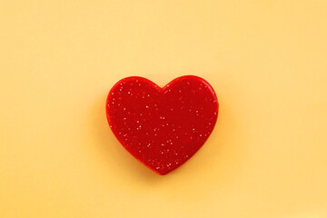 Small red heart on bright yellow background. Love concept. Flat lay.