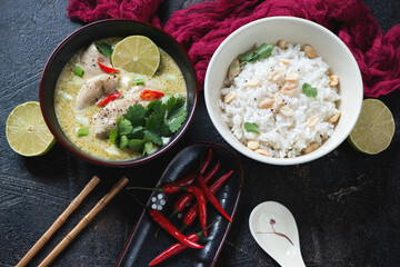Bowls with green chicken curry and white rice, studio shot on a dark-brown stone background, elevated view