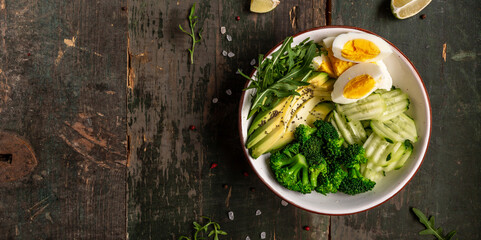 Ketogenic, paleo diet lunch bowl with avocado, cucumber, broccoli and egg. Healthy organic vegan salad. Delicious breakfast or snack, Clean eating, dieting, vegan food concept. top view
