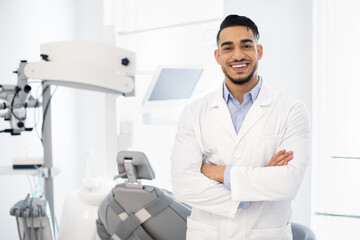 Naklejka na ściany i meble Dental Center. Portrait Of Smiling Middle Eastern Dentist Doctor Posing At Workplace