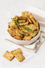 Homemade diet cookies with herbs, flaxseed and spices in a light plate on a light table. Herbal crunchy crackers with green thyme