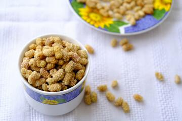 White dried mulberry, dried mulberry in bowl on white background. Copy space. Superfood, vegan, vegetarian food concept. Mulberry berries macro, selective focus. Healthy snack.