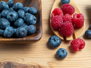 Raspberries and blueberries on a wooden background.