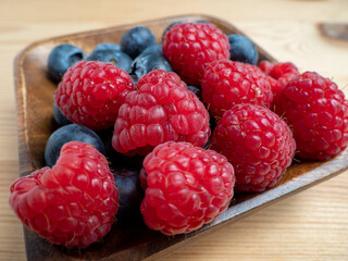 Raspberries and blueberries on a wooden background.