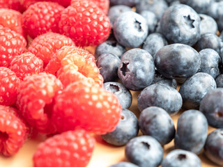 Raspberries and blueberries on a wooden background.