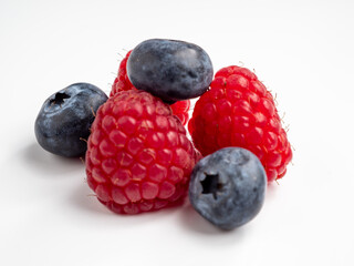 Raspberries and blueberries on a white background.