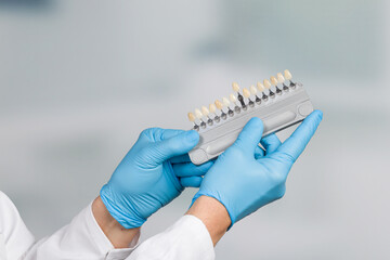 Dentist's hand with shade guide to check/determine veneer of teeth in a dentistry
