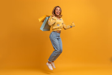 beautiful attractive smiling woman in yellow shirt and jeans with shopping bags