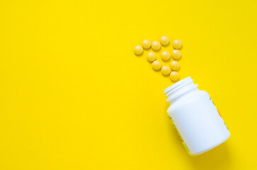 yellow pills from a jar on a yellow background