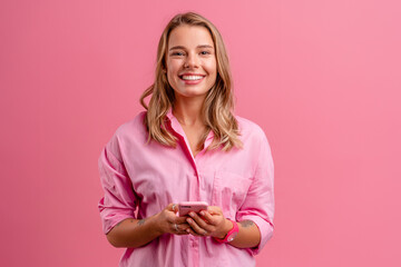 blond pretty woman in pink shirt smiling holding holding using smartphone - Powered by Adobe
