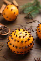 Pomander balls made of tangerines with cloves on wooden table