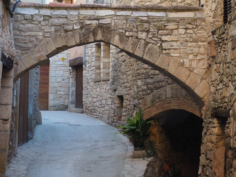 arco ojival dovelado en piedra en una bonita calle del pueblo  medieval de guimera, al fondo arco de medio punto, lerida, españa, europa