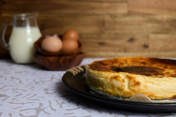 Creamy cheesecake with eggs and milk on brown and white background