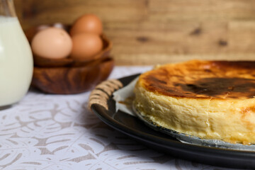 Creamy cheesecake with eggs and milk on brown and white background
