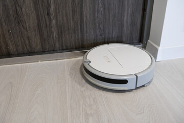 Robotic vacuum cleaner on laminate wood floor in bedroom.