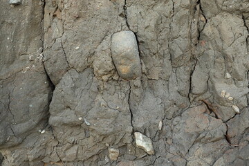 Stone in clay soil with cracks deposit in wall