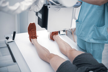 A young man undergoes an x-ray radiograph to identify knee pain in a medical clinic.