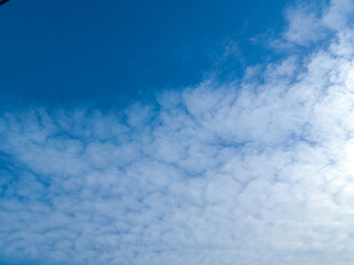 Elegant Cloudy Blue Sky texture, wallpaper background. Beautiful deep blue sky with rounded small soft white clouds in daylight. Landscape image. Altocumulus clouds (Small rows of fluffy ripples).