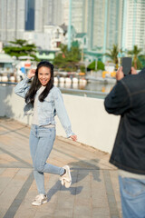 Obraz premium Young man filming his girlfriend dancing outdoors for social media