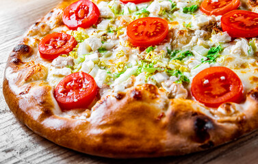 Pizza Caesar with chicken, cheese and tomatoes. Italian pizza on wooden table background