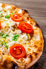 Pizza Caesar with chicken, cheese and tomatoes. Italian pizza on wooden table background