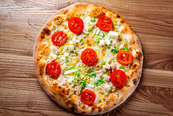 Pizza Caesar with chicken, cheese and tomatoes. Italian pizza on wooden table background
