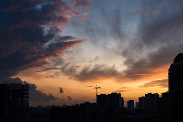Colorful dramatic sky with clouds at sunset over the urban landscape.