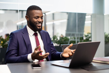 Happy black businessman having video chat, using laptop