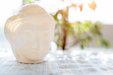 Buddha face. Buddha statue made of white marble with flowers. Concept of peace, meditation, calm...