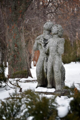 Fototapeta na wymiar Sculptures of lovers, man and woman in winter park, Kyiv, Ukraine. Couple sculpture standing in the garden in the mood of love together in valentine's day.