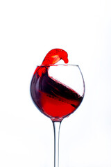 close-up on a transparent wine glass with red wine splashing in it on a white background