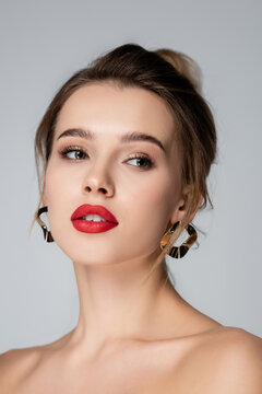 close up portrait of charming woman in golden earrings isolated on grey.