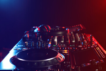 Closeup view of modern DJ controller with headphones on dark background