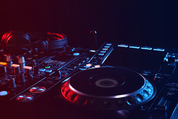 Fototapeta na wymiar Closeup view of modern DJ controller with headphones on black background