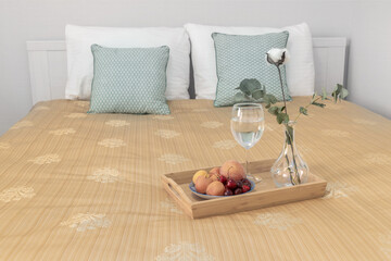 On the bed a tray of fruit and a cotton flower in a vase