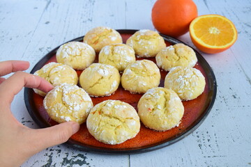 Homemade orange crinkle cookies with powdered sugar icing. Cracked citrus biscuits on white background