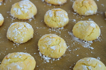 Homemade orange crinkle cookies with powdered sugar on parchment paper