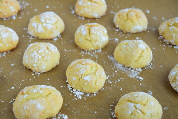 Homemade orange crinkle cookies with powdered sugar on parchment paper